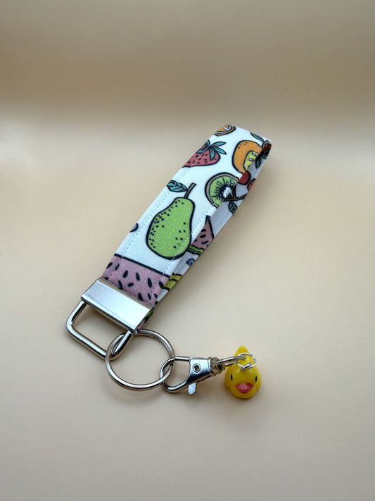 Keychain with fruit patterned strap and small duck charm on a beige background